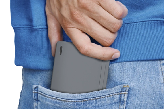 Close-up of rear view of a man putting the folded "Travel 450" keyboard into the pocket of his jeans.