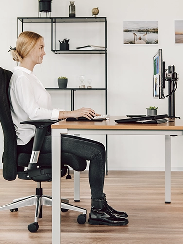 Junge Frau sitzt an einem ergonomisch eingerichteten Schreibtisch mit der Hama Tastatur "EKC-400" mit Handballenauflage
