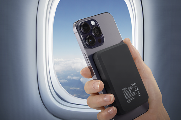 Person holding his smartphone with wireless power pack in front of a airplain window