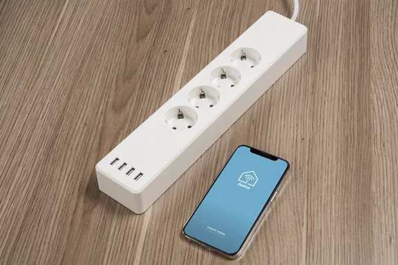 The smartphone is next to the power strip.